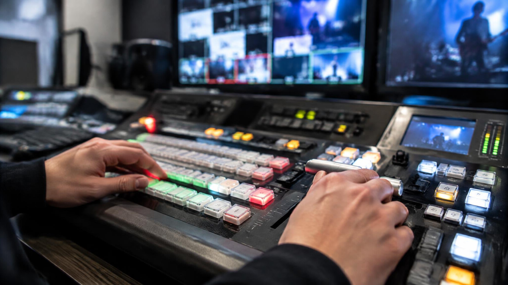Close-up of hands operating a live broadcast switcher panel with sliders and buttons